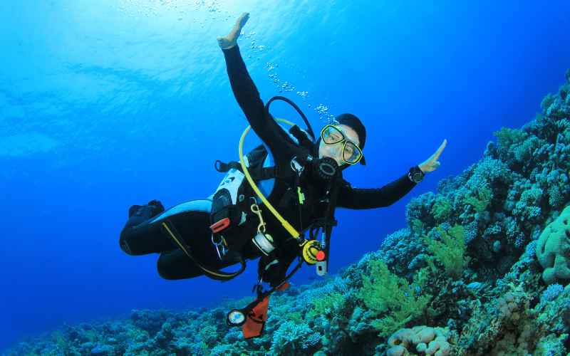 Scuba Diver waving her hands at the Tuamotu Archipelago reefs